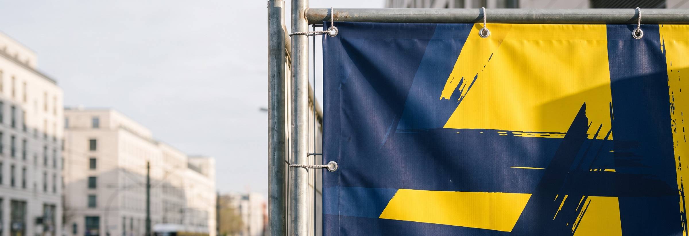 Bedrucktes PVC-Bauzaunbanner mit Ösen an einer Straße
